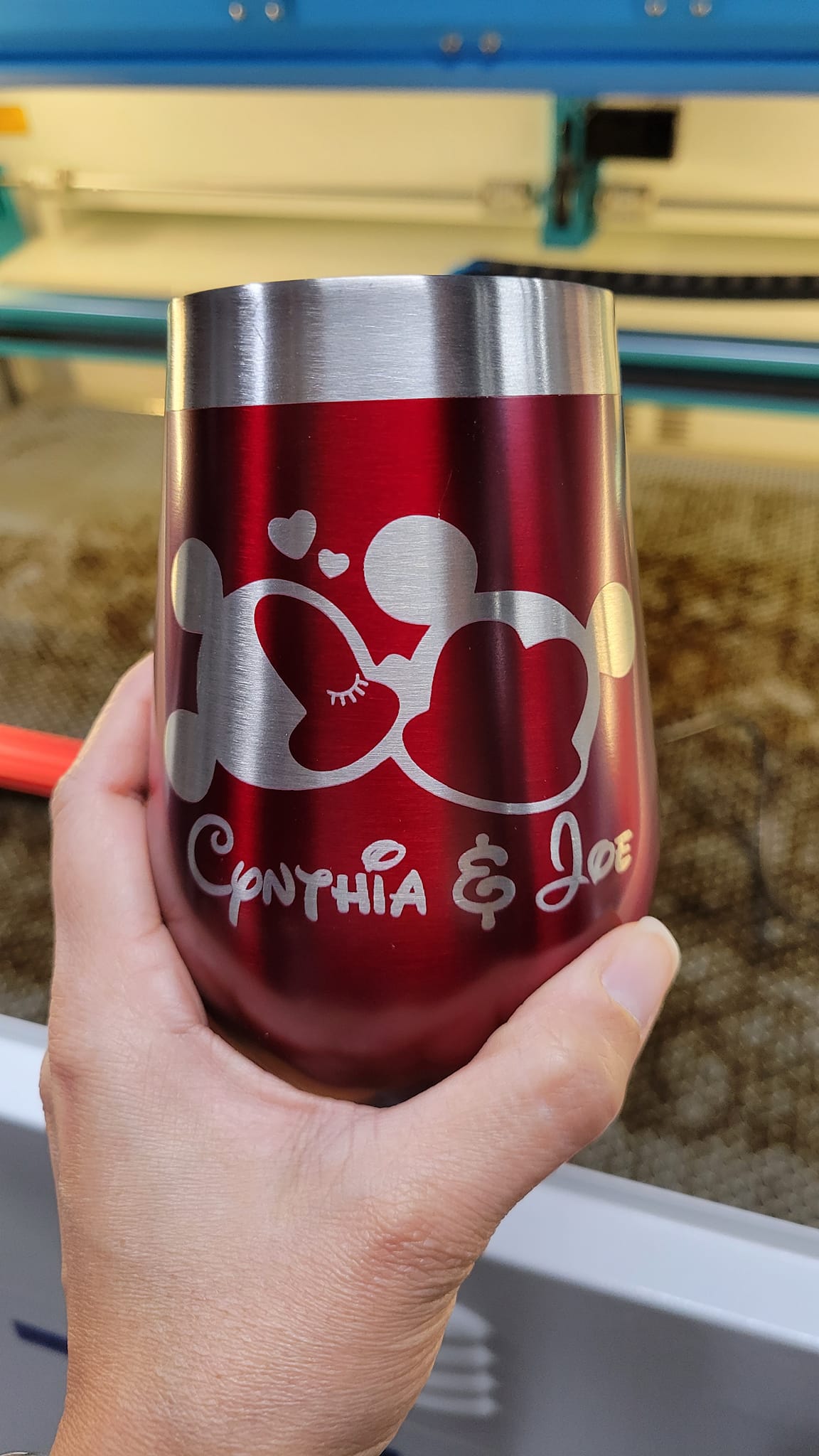 A laser engraver precisely etches a design onto a stainless steel tumbler while safety guards ensure a secure work environment